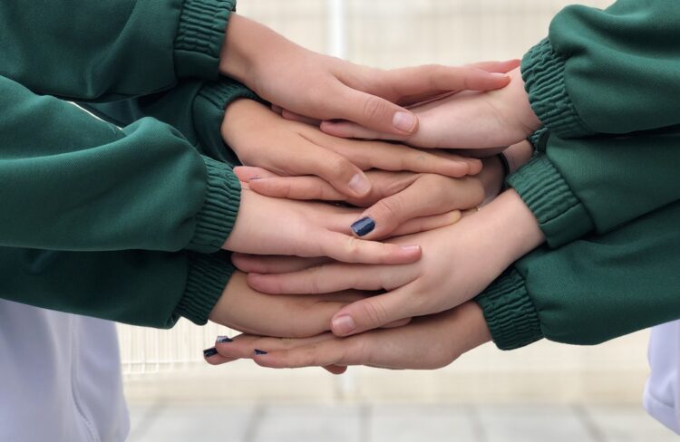 Manos de alumnos unidas en el Colegio Quercus de Boadilla, representando el aprendizaje cooperativo y la solidaridad